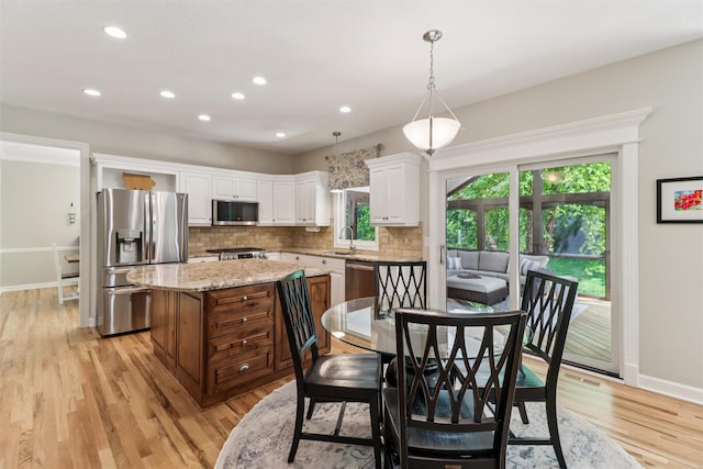 7016 Harbour Dr, Johnston, IA 50131 - kitchen with stainless steel appliances, healthy amount of natural light, a kitchen island, light wood-style floors, and recessed lighting