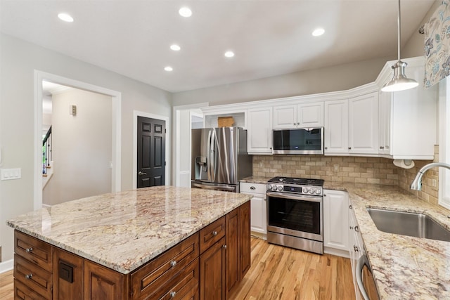 7016 Harbour Dr, Johnston, IA 50131 - kitchen with appliances with stainless steel finishes, light wood-style floors, white cabinetry, a kitchen island, and recessed lighting