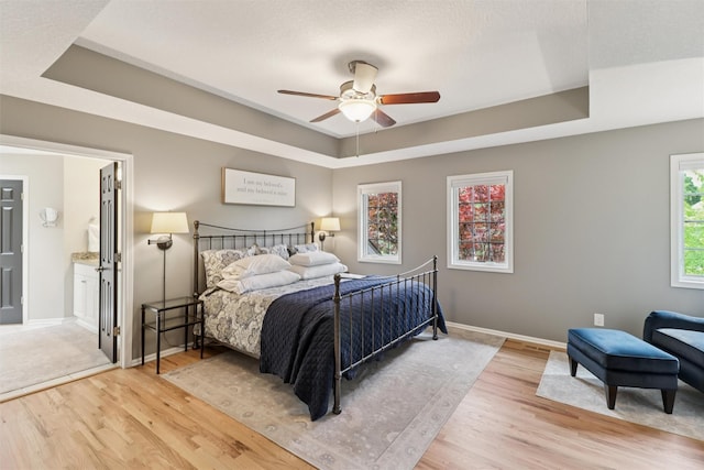 7016 Harbour Dr, Johnston, IA 50131 - bedroom with a raised ceiling, light wood finished floors, ensuite bathroom, and a ceiling fan
