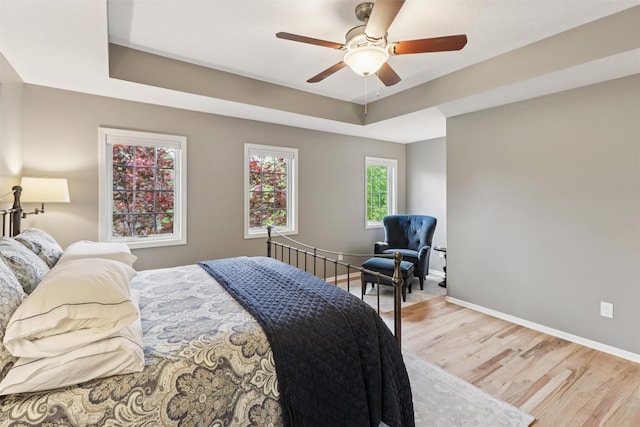 7016 Harbour Dr, Johnston, IA 50131 - bedroom featuring light wood-style flooring, a tray ceiling, and a ceiling fan