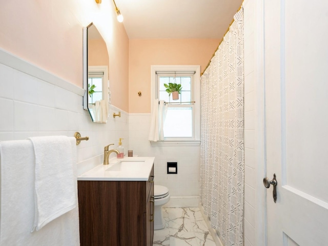 1655 NW Dr, Des Moines, IA 50310 - full bath featuring vanity, tile walls, marble finish flooring, and a wainscoted wall