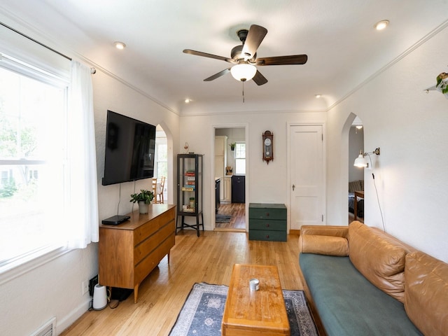 1655 NW Dr, Des Moines, IA 50310 - living room with arched walkways, healthy amount of natural light, a ceiling fan, light wood-type flooring, and crown molding