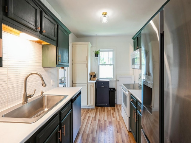 1655 NW Dr, Des Moines, IA 50310 - kitchen with stainless steel appliances, light countertops, backsplash, light wood-type flooring, and green cabinets
