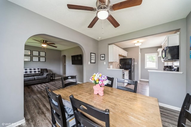 3411 61st St, Des Moines, IA 50322 - dining space with arched walkways, ceiling fan, and dark wood-style floors