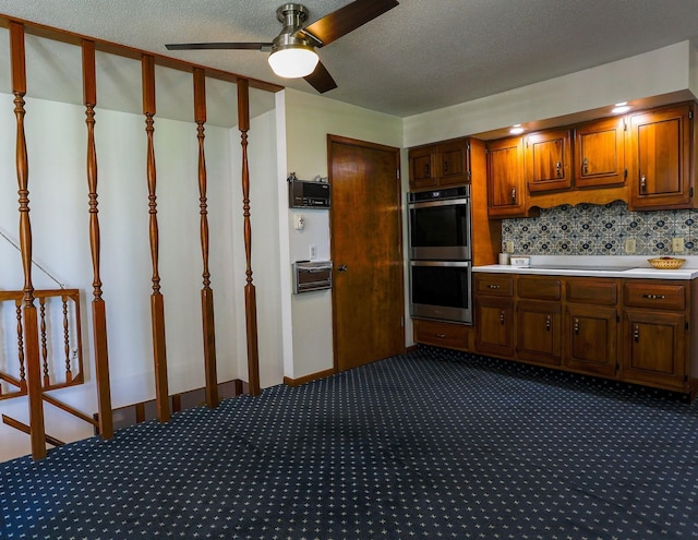 1108 Hillcrest Ct, Chariton, IA 50049 - kitchen with double oven, dark colored carpet, light countertops, a ceiling fan, and brown cabinets
