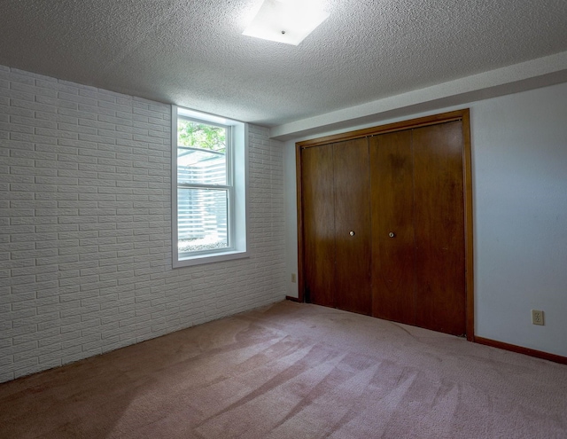 1108 Hillcrest Ct, Chariton, IA 50049 - unfurnished bedroom featuring a textured ceiling, carpet floors, a closet, and brick wall