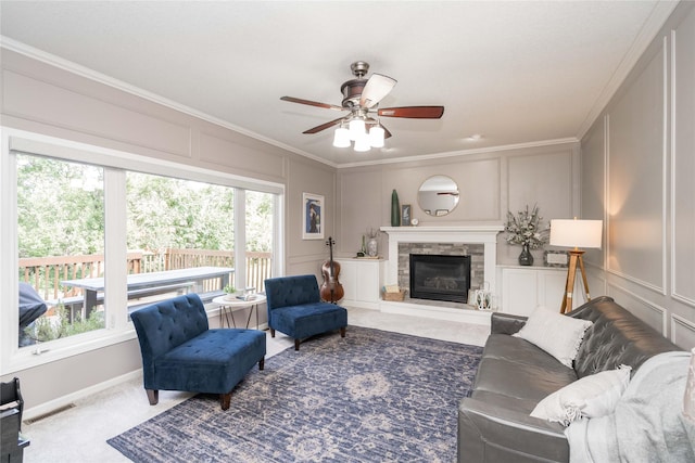 3605 80th St, Urbandale, IA 50322 - carpeted living area with a decorative wall, ceiling fan, ornamental molding, and a stone fireplace