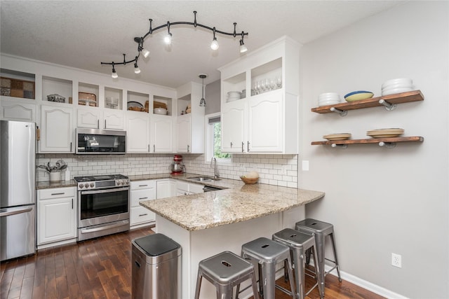 3605 80th St, Urbandale, IA 50322 - kitchen featuring appliances with stainless steel finishes, a peninsula, white cabinetry, open shelves, and decorative backsplash