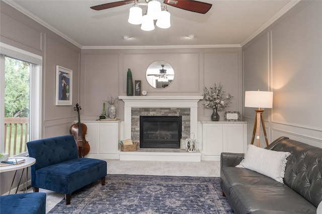 3605 80th St, Urbandale, IA 50322 - living area featuring a decorative wall, ceiling fan, ornamental molding, carpet flooring, and a stone fireplace