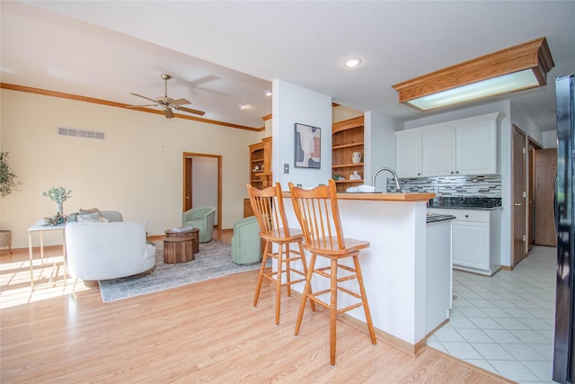 5925 Ep True Pkwy Unit 36, West Des Moines, IA 50266 - kitchen with a kitchen bar, white cabinets, ceiling fan, light wood-style floors, and open floor plan