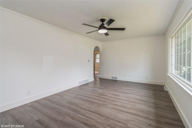 1212 Burnham Ave, Des Moines, IA 50315 - empty room featuring arched walkways, ceiling fan, wood finished floors, and crown molding