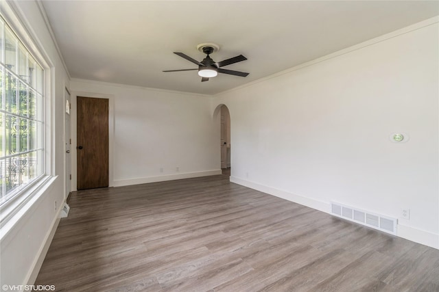 1212 Burnham Ave, Des Moines, IA 50315 - empty room with arched walkways, healthy amount of natural light, ceiling fan, crown molding, and wood finished floors