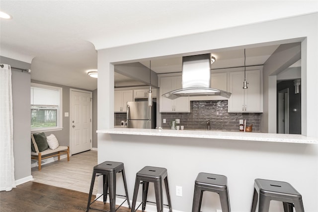2512 Boston Ave, Des Moines, IA 50310 - kitchen featuring freestanding refrigerator, extractor fan, a kitchen bar, and tasteful backsplash