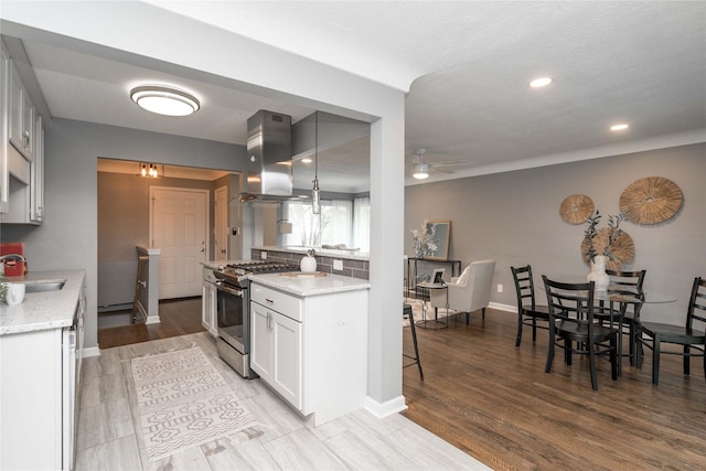 2512 Boston Ave, Des Moines, IA 50310 - kitchen with stainless steel gas stove, island exhaust hood, a ceiling fan, light stone counters, and recessed lighting