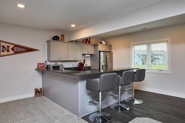 685 Indian Ridge Dr, Waukee, IA 50263 - kitchen with stainless steel fridge with ice dispenser, a breakfast bar, built in microwave, dark countertops, and recessed lighting
