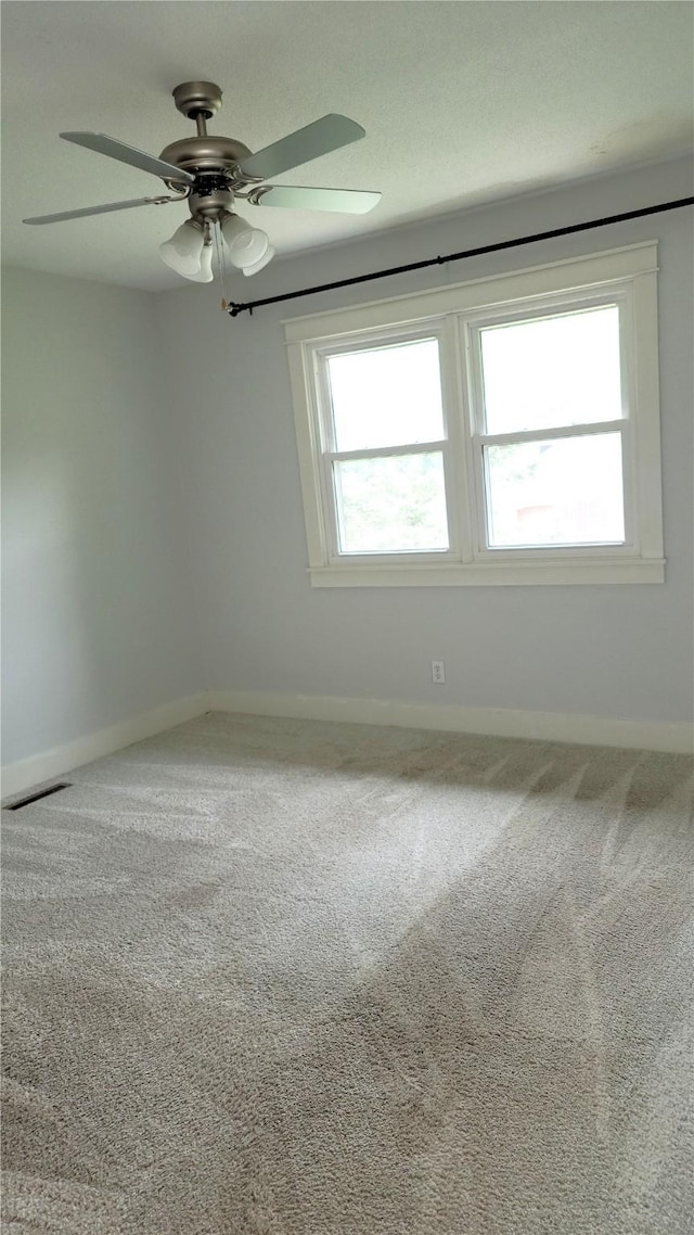 623 E 18th St N, Newton, IA 50208 - empty room featuring a ceiling fan, healthy amount of natural light, and carpet flooring