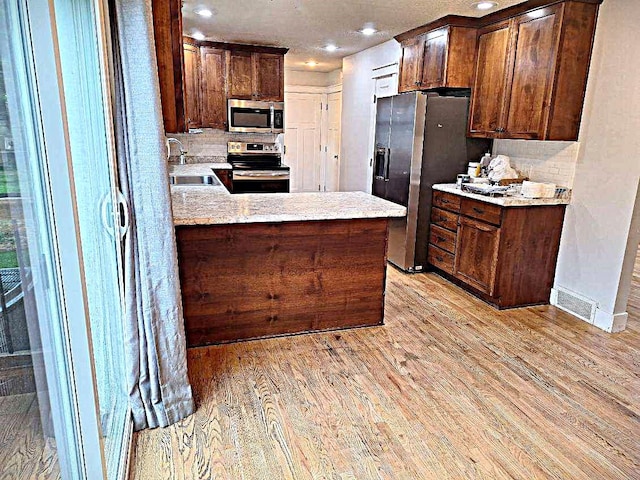 623 E 18th St N, Newton, IA 50208 - kitchen featuring stainless steel appliances, light wood-style flooring, tasteful backsplash, recessed lighting, and a peninsula