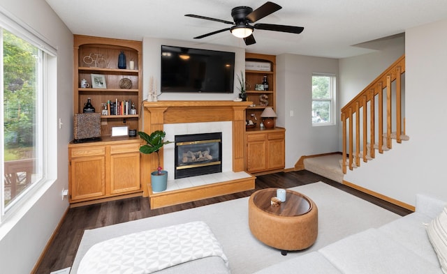 14449 Briarwood Ln, Urbandale, IA 50323 - living area featuring dark wood-style floors, a fireplace, a ceiling fan, and stairs