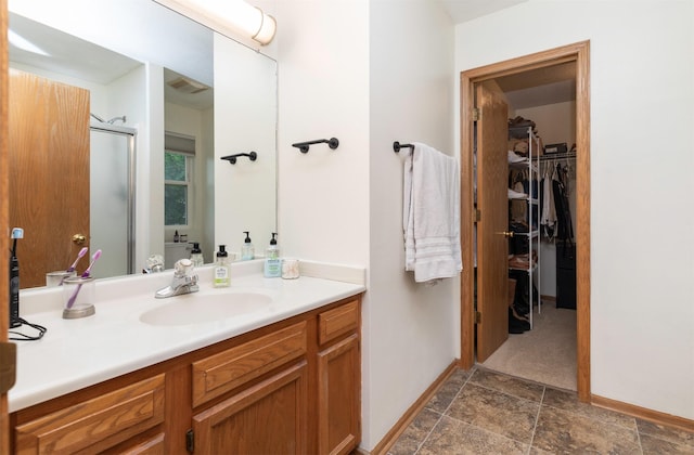 14449 Briarwood Ln, Urbandale, IA 50323 - full bathroom with vanity, a stall shower, a walk in closet, and stone finish floors