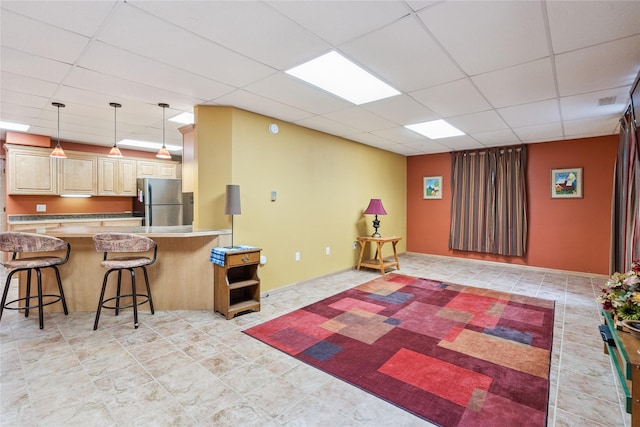 7 Hobart Pl, Grinnell, IA 50112 - kitchen with freestanding refrigerator, a paneled ceiling, a breakfast bar, a peninsula, and pendant lighting