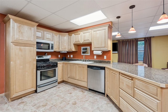 7 Hobart Pl, Grinnell, IA 50112 - kitchen featuring stainless steel appliances, light brown cabinetry, a paneled ceiling, a peninsula, and pendant lighting