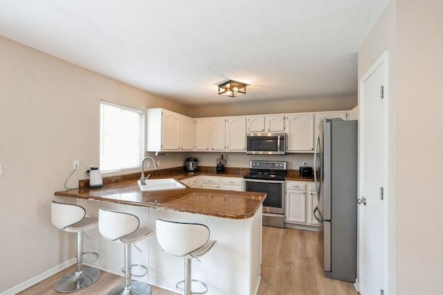 681 63rd St, West Des Moines, IA 50266 - kitchen featuring appliances with stainless steel finishes, a peninsula, white cabinetry, and light wood-style floors