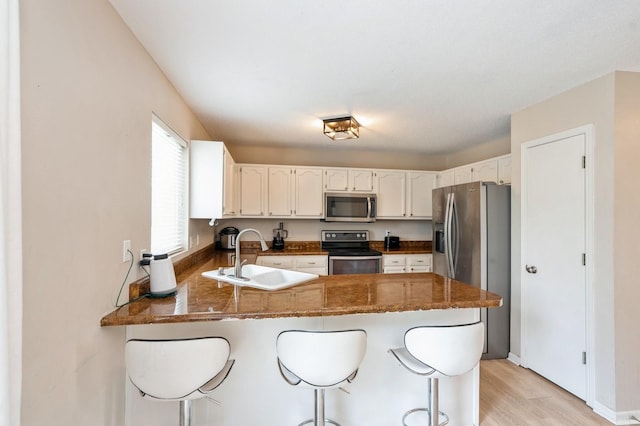 681 63rd St, West Des Moines, IA 50266 - kitchen featuring stainless steel appliances, a peninsula, light wood-style flooring, and a breakfast bar