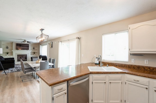 681 63rd St, West Des Moines, IA 50266 - kitchen featuring dishwasher, a glass covered fireplace, a peninsula, light wood-style floors, and open floor plan