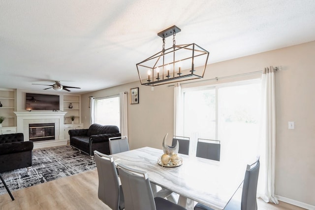 681 63rd St, West Des Moines, IA 50266 - dining room with ceiling fan, light wood-style floors, a glass covered fireplace, and built in shelves