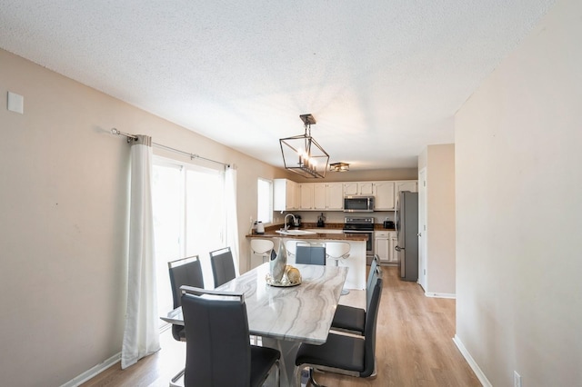 681 63rd St, West Des Moines, IA 50266 - dining area featuring a chandelier, light wood-style floors, and a textured ceiling