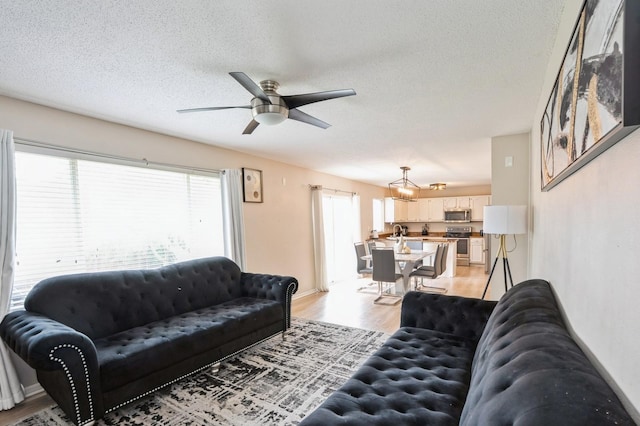 681 63rd St, West Des Moines, IA 50266 - living room featuring light wood finished floors, a ceiling fan, a textured ceiling, and a chandelier