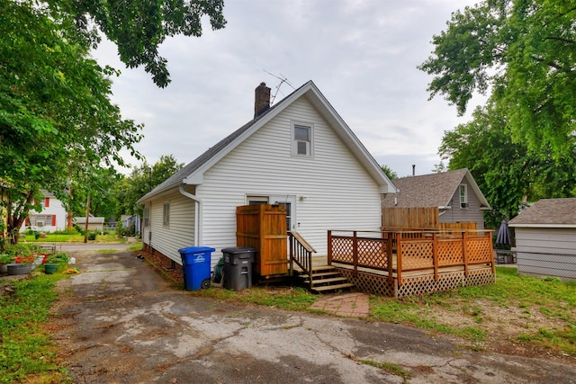 816 Boyd St, Des Moines, IA 50316 - rear view of property with a chimney, a wooden deck, driveway, and roof with shingles