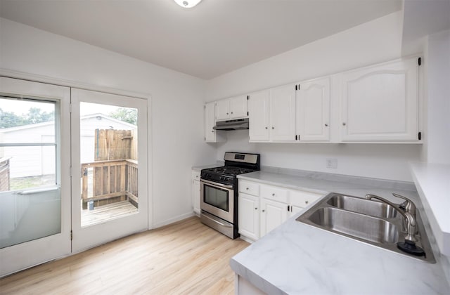 816 Boyd St, Des Moines, IA 50316 - kitchen featuring stainless steel gas range, under cabinet range hood, light wood-style flooring, and white cabinets