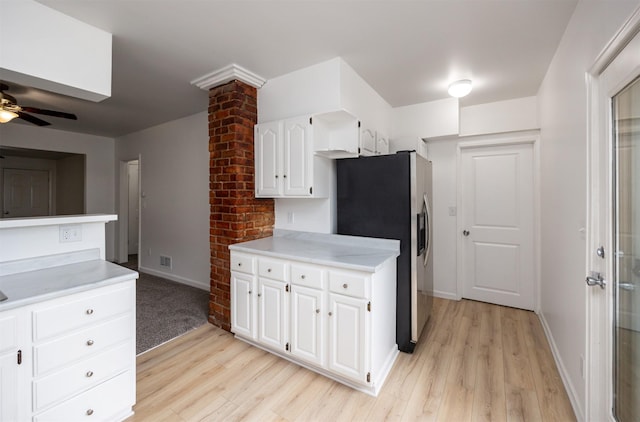 816 Boyd St, Des Moines, IA 50316 - kitchen with stainless steel fridge, light wood-type flooring, light countertops, and white cabinets