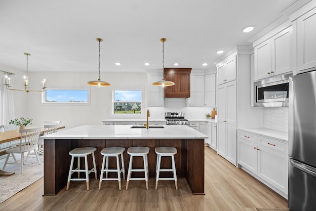 2309 NW 29th St, Ankeny, IA 50023 - kitchen with appliances with stainless steel finishes, an island with sink, light wood finished floors, backsplash, and recessed lighting