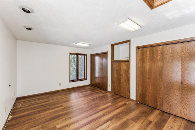 6542 Washington Ave, Windsor Heights, IA 50324 - unfurnished bedroom with two closets, wood finished floors, and a textured ceiling
