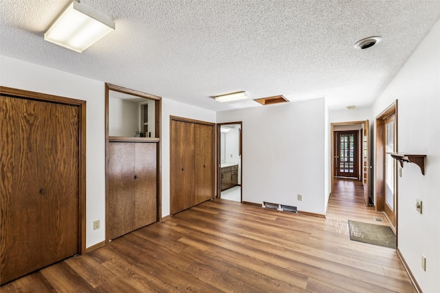 6542 Washington Ave, Windsor Heights, IA 50324 - unfurnished bedroom featuring wood finished floors, two closets, and a textured ceiling