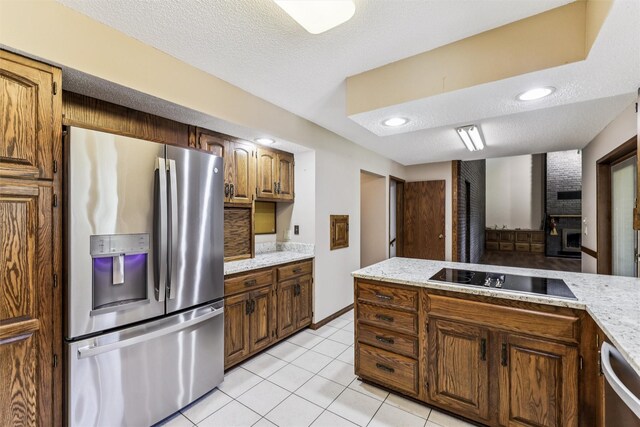 6542 Washington Ave, Windsor Heights, IA 50324 - kitchen with appliances with stainless steel finishes, light tile patterned floors, a textured ceiling, and brown cabinets