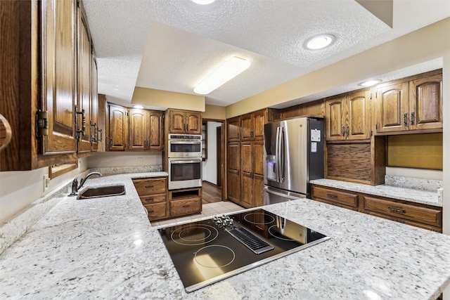 6542 Washington Ave, Windsor Heights, IA 50324 - kitchen with appliances with stainless steel finishes, a textured ceiling, and brown cabinetry