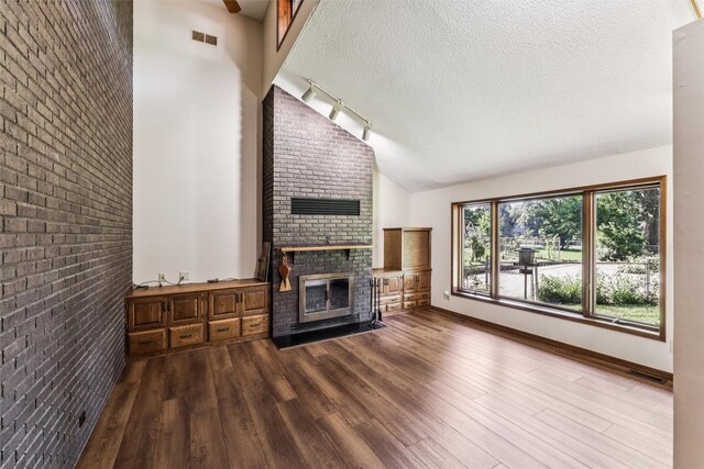 6542 Washington Ave, Windsor Heights, IA 50324 - unfurnished living room with a fireplace, dark wood-style flooring, a textured ceiling, lofted ceiling, and brick wall