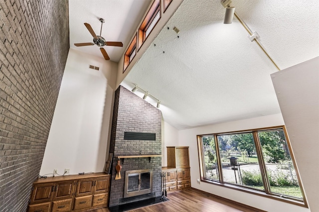 6542 Washington Ave, Windsor Heights, IA 50324 - unfurnished living room with vaulted ceiling, track lighting, a ceiling fan, a fireplace, and wood finished floors