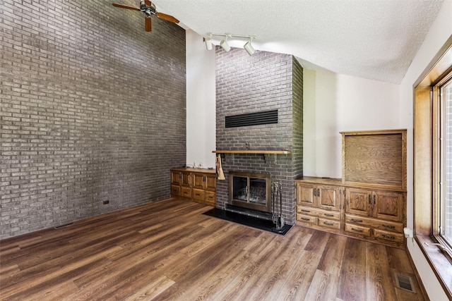 6542 Washington Ave, Windsor Heights, IA 50324 - unfurnished living room with a brick fireplace, a textured ceiling, wood finished floors, ceiling fan, and brick wall
