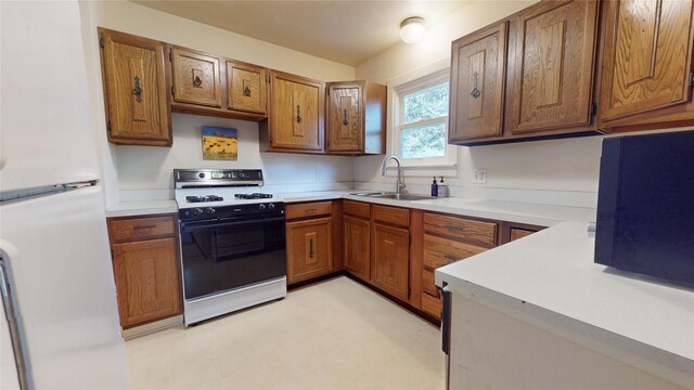 3827 Carpenter Ave, Des Moines, IA 50311 - kitchen featuring gas range, freestanding refrigerator, light countertops, and brown cabinets