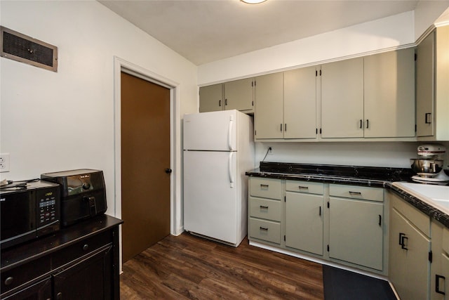 4207 Madison Ave, Des Moines, IA 50310 - kitchen featuring freestanding refrigerator, black microwave, dark wood-style flooring, and dark countertops