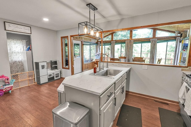 1018 S 5th St, Knoxville, IA 50138 - kitchen featuring light countertops, wood finished floors, pendant lighting, a kitchen island with sink, and stainless steel stove
