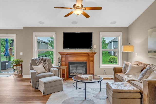 2501 NE Ewing Ct, Grimes, IA 50111 - living area featuring healthy amount of natural light, light wood finished floors, a glass covered fireplace, and ceiling fan