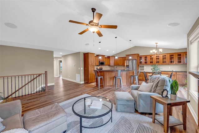 2501 NE Ewing Ct, Grimes, IA 50111 - living room with lofted ceiling, light wood-style floors, a chandelier, and ceiling fan