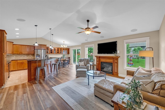 2501 NE Ewing Ct, Grimes, IA 50111 - living room with vaulted ceiling, a glass covered fireplace, plenty of natural light, a ceiling fan, and light wood-style floors