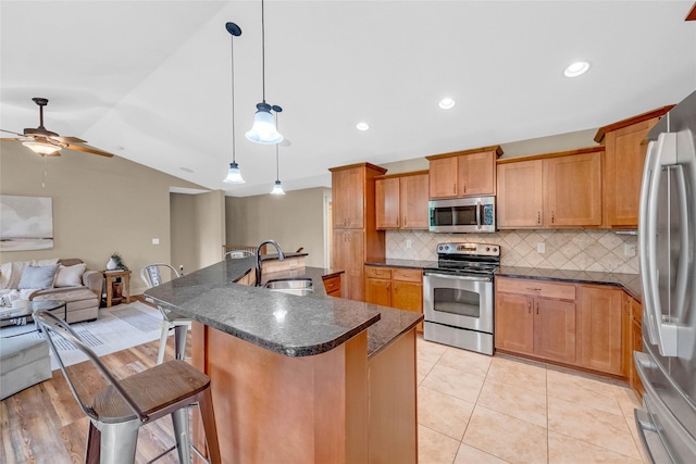2501 NE Ewing Ct, Grimes, IA 50111 - kitchen with stainless steel appliances, open floor plan, a kitchen bar, backsplash, and ceiling fan
