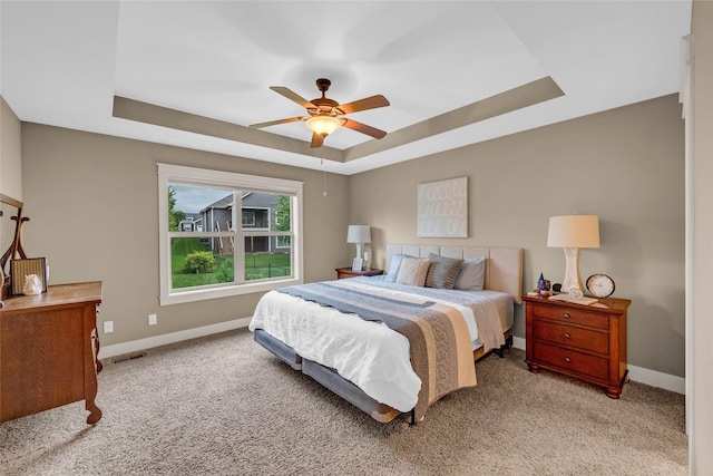 2501 NE Ewing Ct, Grimes, IA 50111 - bedroom featuring a tray ceiling, light carpet, and a ceiling fan